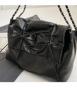 Détail du sac cabas en cuir froissé noir brillant avec nœuds et bandoulière chaîne argent