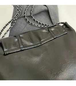 Détail du sac cabas en cuir noir avec bandoulière chaîne argentée et coutures raffinées