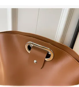 Detail of caramel leather tote bag with metal ring handle and rivet reinforcement