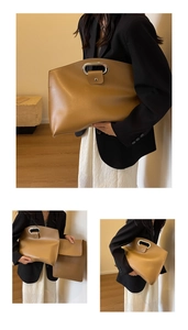 Detail of camel leather envelope bag featuring metal handle and engraved logo