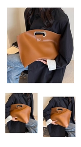 Detail of a brown leather tote with a unique silver metal oval handle and smooth texture