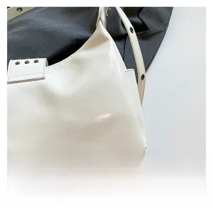 Close-up of white punk style crossbody bag featuring metallic rivet details and premium texture