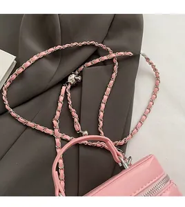 Pink box bag with metal chain strap and leather handle against grey suit background