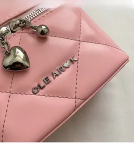 Detail of pink quilted leather texture and silver metal heart charms on the box handbag