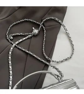Detail of silver chain strap with adjustable diamond quilted ball on metallic bag