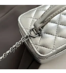 Detail of silver quilted leather bag showing diamond stitching and metal chain strap