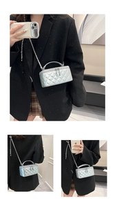 Macro view of silver quilted box bag with metal chain strap and dual zippers