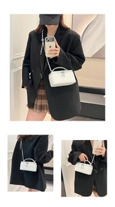 Detail of white quilted crossbody bag showing double zipper and silver metal chain strap