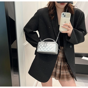 Silver quilted mini crossbody bag with metal chain strap worn by a female model