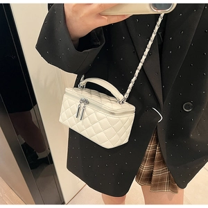 Close-up of white quilted mini bag featuring silver chain strap and top handle detail