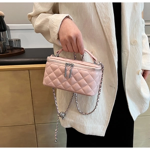 Close-up of pink quilted crossbody bag with silver chain and metal ball adjuster