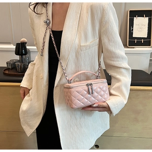Close-up of pink quilted mini bag with adjustable chain strap worn by a model