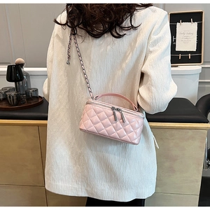 Pink quilted leather mini vanity bag with chain strap shown on model in cozy room
