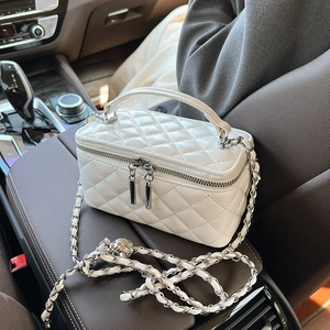 Elegant white quilted crossbody bag with silver chain strap on a car interior background