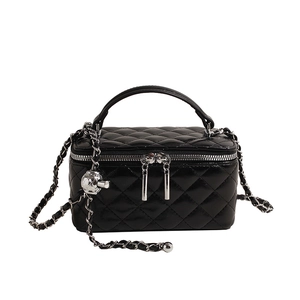 Quilted black leather handbag with gold chain strap and top handle on white background