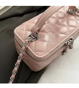 Close-up of pink quilted box bag with silver heart charms and dual zipper detail