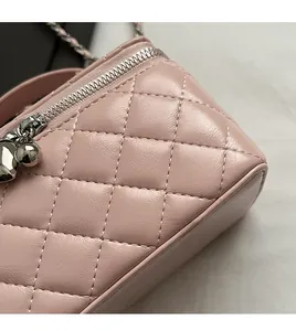 Detail of pink quilted leather bag featuring a heart-shaped silver zipper puller