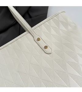 Detail of hand-stitched edges and geometric diamond texture on white leather tote bag