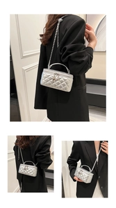 Detail of silver quilted vanity bag featuring chain strap and heart charm detail