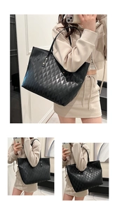 Detail of black quilted tote bag showing textured diamond pattern and gold rivets