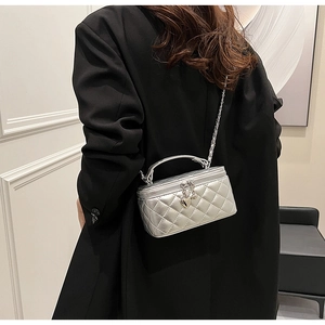 Detail of silver quilted vanity case with chain strap and heart charm on black blazer