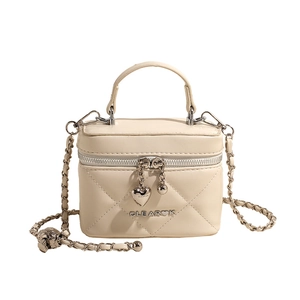 Quilted beige vanity bag with gold chain strap and heart charm in a centered view