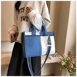 Détail du cabas en denim bicolore avec fermoir rotatif doré et bandoulière réglable