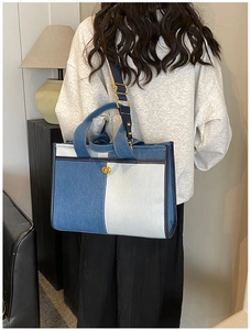 Détail d'un sac cabas en denim bicolore avec fermoir doré et bandoulière réglable