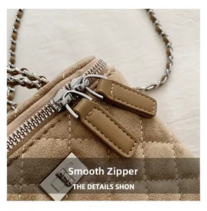 Macro view of smooth double zippers and quilted texture on brown suede crossbody bag