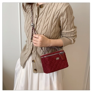 Detail of burgundy quilted velvet box bag with silver chain and metal handle shown on model