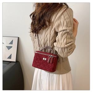 Detail view of red velvet quilted box bag with elegant chain strap and woven top handle