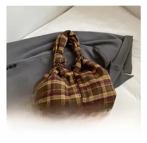 Close-up of retro brown and yellow plaid tote bag with twisted handle on grey blazer