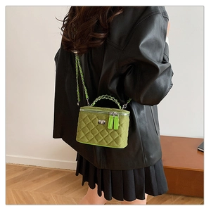 Close-up of green quilted velvet mini bag with gold chain strap on model shoulder