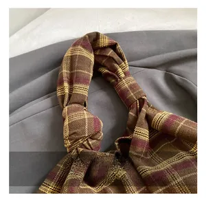 Detail shot of the knotted fabric handle and plaid tweed texture on a large tote bag