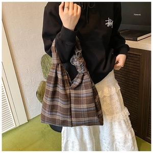 Detail of checkered knot tote bag featuring brown and blue plaid fabric with knotted handle