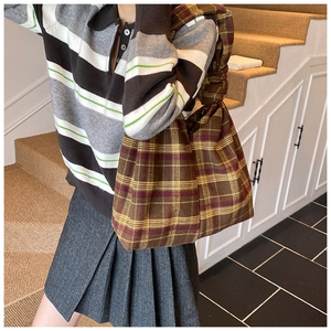 Detailed view of plaid tote bag with pleated handle styled in a vintage autumn outfit