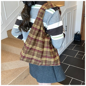 Detail of vintage brown plaid knit tote bag with wide shoulder strap worn by a model