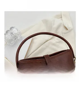 Vue détaillée d'un sac seau marron vintage avec fermoir doré rotatif et texture cuir raffinée
