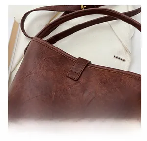 Gros plan détaillé du sac seau en cuir marron montrant les coutures et le grain de cuir