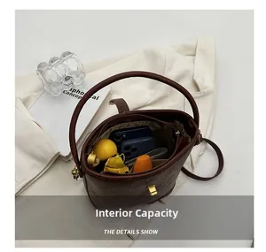 Vue détaillée du compartiment intérieur spacieux du sac seau marron avec des objets du quotidien