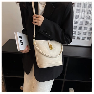 Close-up of white textured bucket bag with golden lock and dual shoulder straps
