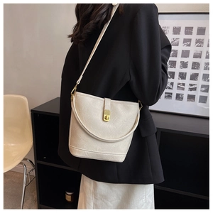 Chic cream-colored bucket bag detail featuring a gold twist lock and smooth leather texture