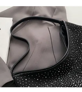 Detalle del bolso de hombro negro con strass y costuras en contraste en la correa de cuero