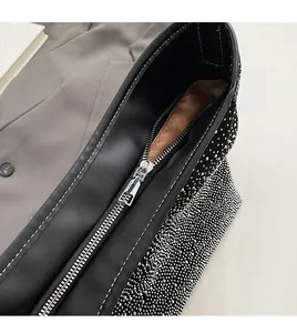 Detalle de la cremallera metálica y los diamantes de imitación en un bolso de mano negro