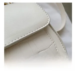 Close-up of white embossed leather handbag showing precise stitching and crocodile texture