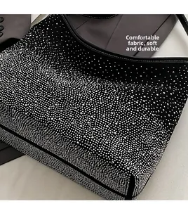 Detalle de diamantes de imitación plateados en bolso negro con asa de costura blanca