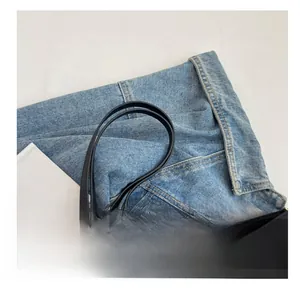 Détail de la poignée souple du sac fourre-tout noir montrant la couture et texture