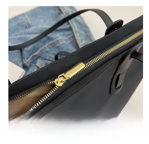 Gros plan sur la fermeture éclair dorée et la texture en nylon d'un sac cabas noir