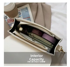 Detailed interior view of a stylish ivory saddle bag showing multiple compartments