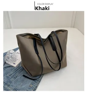 Détail d'un grand sac cabas kaki avec des bandoulières noires et accessoires de décor
